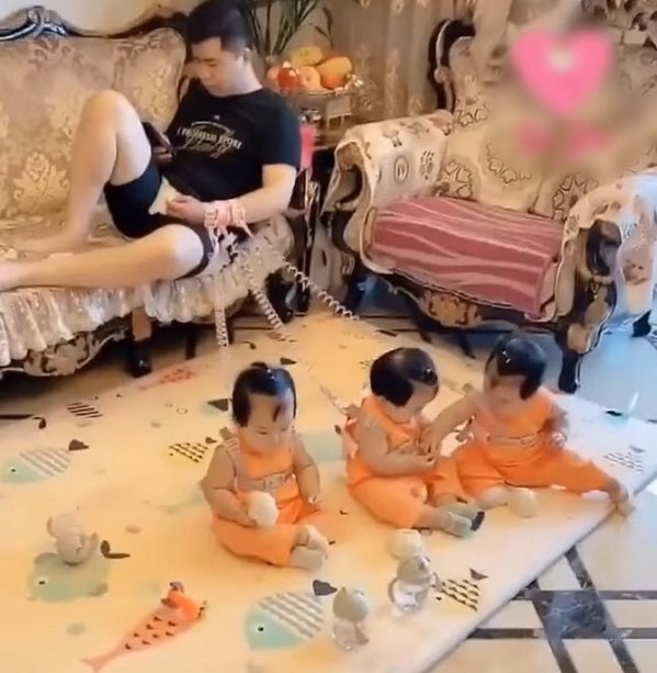  Người bố trẻ phải nghĩ ra đủ chiêu trò để trông cặp sinh 3 khiến nhiều người không khỏi bật cười. (Ảnh: Sohu)