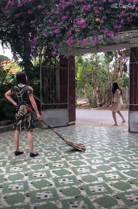  Người mẹ cầm chổi "quét" gái cưng ra tận ngoài cổng.&nbsp;(Ảnh: Chụp màn hình video TikTok N.)