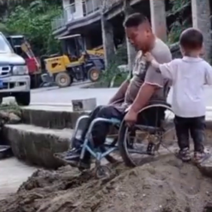  Em bé vội chạy tới khi thấy bố đang cố điều khiển xe lăn qua gò đất. (Ảnh: Chụp màn hình Douyin)