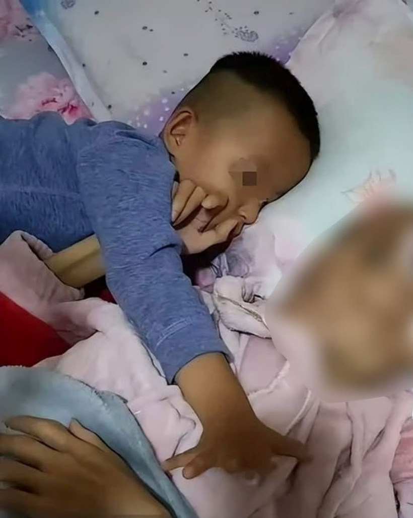 Cậu bé Yang Yucheng &nbsp;nằm cạnh mẹ, ngây thơ hỏi tại sao mẹ không nói chuyện với mình. Ảnh: Douyin