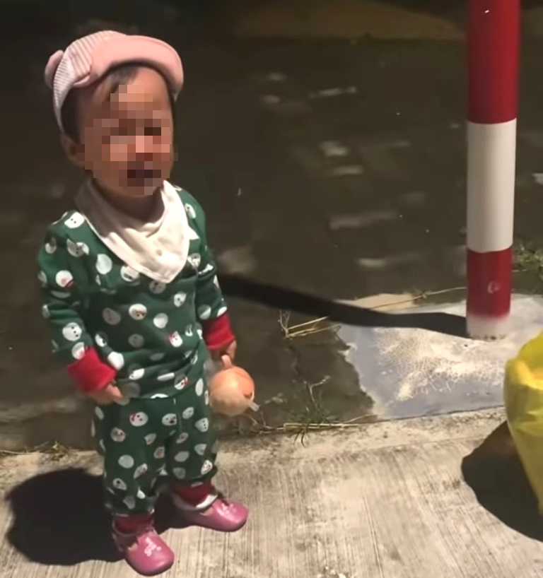 Bé gái hơn 1 tuổi đứng khóc bên đường khi bị mẹ bỏ rơi trong đêm. Ảnh: Sức khoẻ & Đời sống