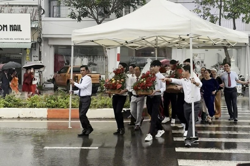 Một số người trong đoàn đã nhanh trí nghĩ ra cách dùng rạp cưới để che chắn, giúp cả đoàn nhà trai di chuyển an toàn vào trong lễ hỏi. Ảnh: Báo Dân trí.