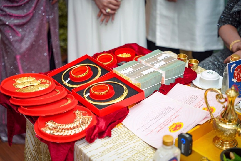 Trang sức vàng, nhiều xấp tiền mặt và 2 tờ sổ hồng được đặt trên bàn. Ảnh: Báo Thanh niên.
