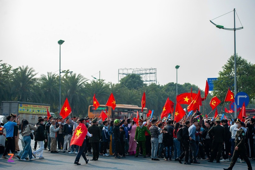 Người dân mang theo cờ Tổ quốc, trống, kèn, vật dụng cổ động để chào đón tuyển Việt Nam. Một số bậc phụ huynh còn đưa theo con nhỏ, hòa chung bầu không khí cổ động náo nhiệt.