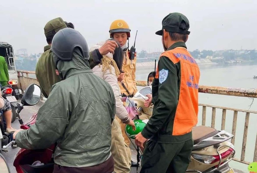 Lực lượng chức năng có mặt kịp thời, ngăn cản người mẹ ôm con trai định nhảy xuống sông. Ảnh: Hà Nội Mới