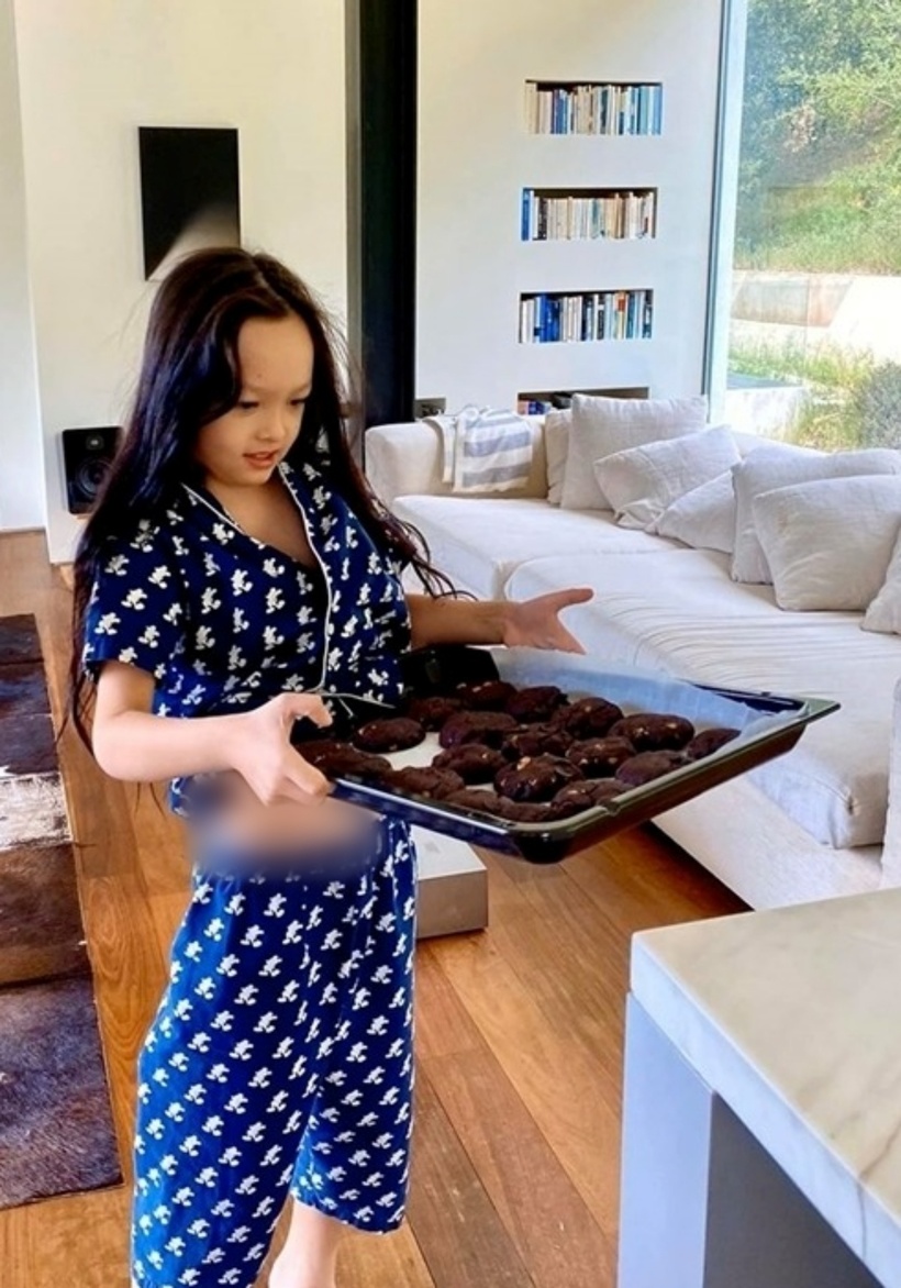 Phòng khách nằm ở tầng 1, nối liền với khu vực bếp và phòng ăn. Nơi này đặt một bộ sofa mút bọc vải trắng, giá sách ốp tường kế bên, trưng bày một số cuốn đặc sắc. Ngồi tại đây, mọi người có thể ngắm cảnh ngoài vườn, đọc sách hay nghe nhạc.