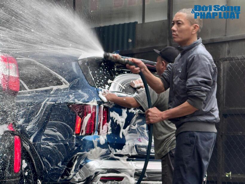 Hàng loạt ô tô, xe máy xếp hàng từ sáng sớm chờ đến lượt. Bên trong bãi đỗ ô tô, hai nam nhân viên liên tục cầm vòi xịt, làm sạch từng chi tiết xe.