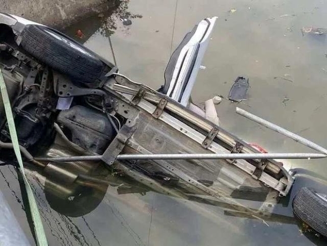 Chiếc xe nằm nghiêng dưới sông. Ảnh: Thanh niên và Tiền phong