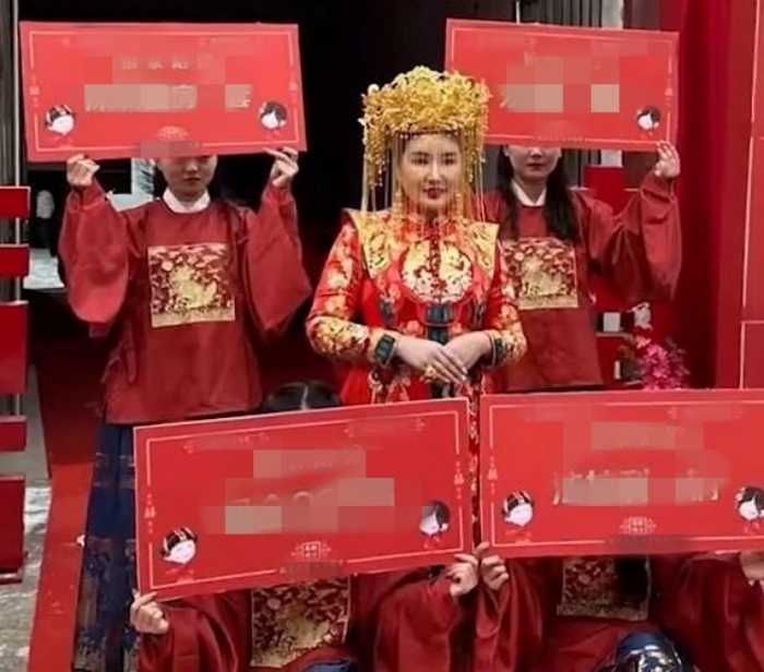 4 người, mặc đồng phục màu đỏ, tay cầm bảng ghi danh sách của hồi môn mà cô dâu tự chuẩn bị. Ảnh: SCMP.