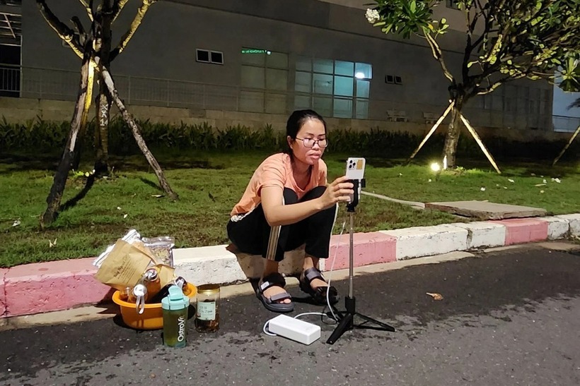 Người mẹ trẻ ngồi ở hành lang, có lúc lại ngồi ở lối đi trong khuôn viên bệnh viện để livestream. Ảnh: Phụ nữ số.