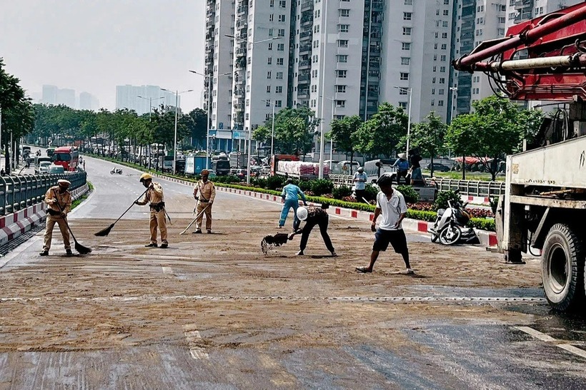 CSGT cùng người dân rải cát, xử lý vết dầu loang trên mặt cầu để người tham gia giao thông tránh gặp nguy hiểm khi di chuyển qua. (Ảnh: Cơ quan công an)