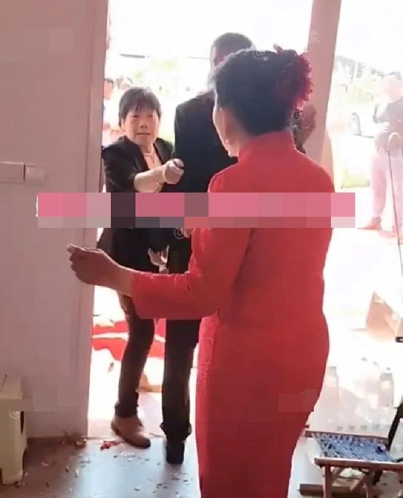 Vừa nhìn thấy cô dâu, người mẹ giơ chiếc túi trên tay lên định đánh nhưng con trai đã cố gắng ngăn lại. Ảnh: Saostar.