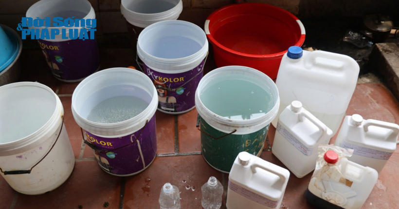 Các dụng cụ và dung dịch để pha chế, sản xuất mỹ phẩm giả để dưới sàn nhà, đựng bằng các thùng sơn đã qua sử dụng.