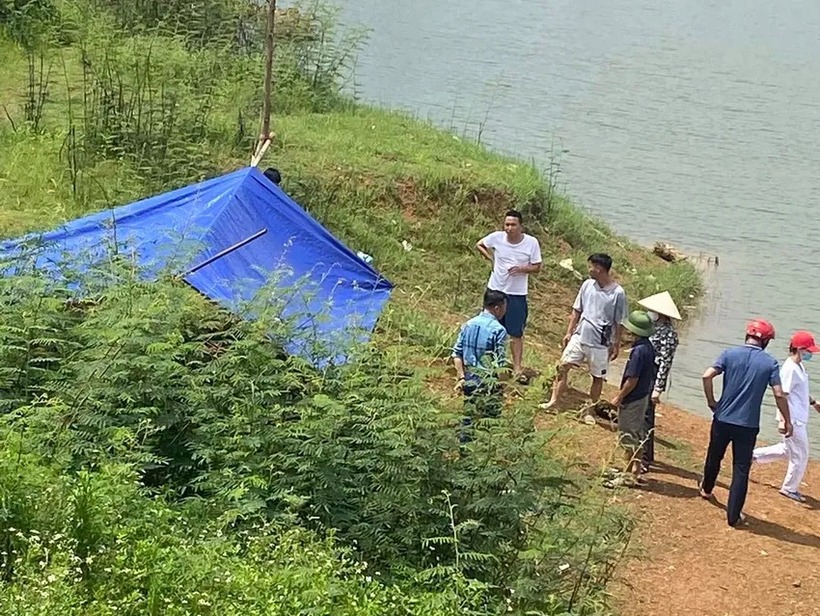 Người dân và lực lượng chức năng đưa hai người đuối nước lên bờ. (Ảnh: Pháp luật TP.HCM)