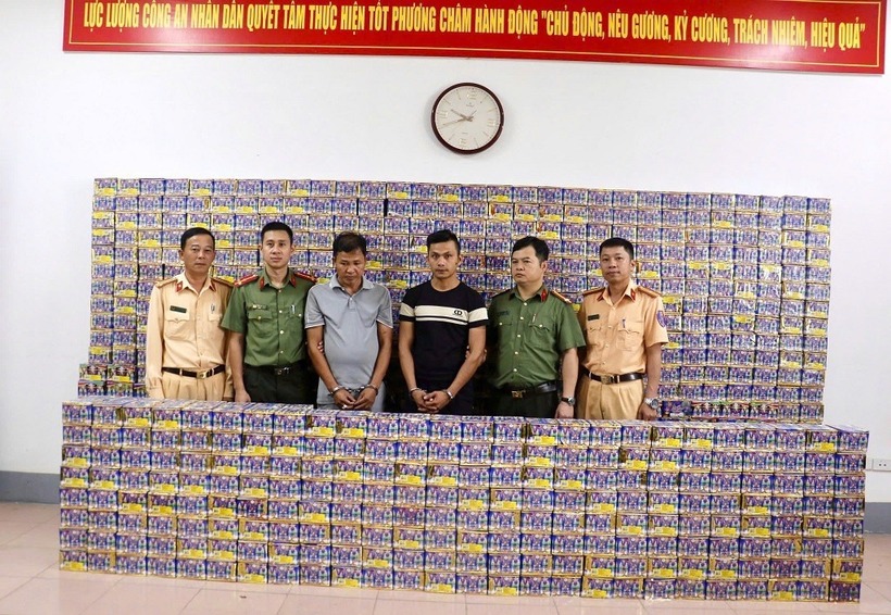 Đối tượng Hoàng Cảnh Ước (thứ 3 từ trái sang) và Cao Thanh Hòa (thứ 3 từ phải sang) cùng tang vật tại cơ quan điều tra. (Ảnh: Dân trí)