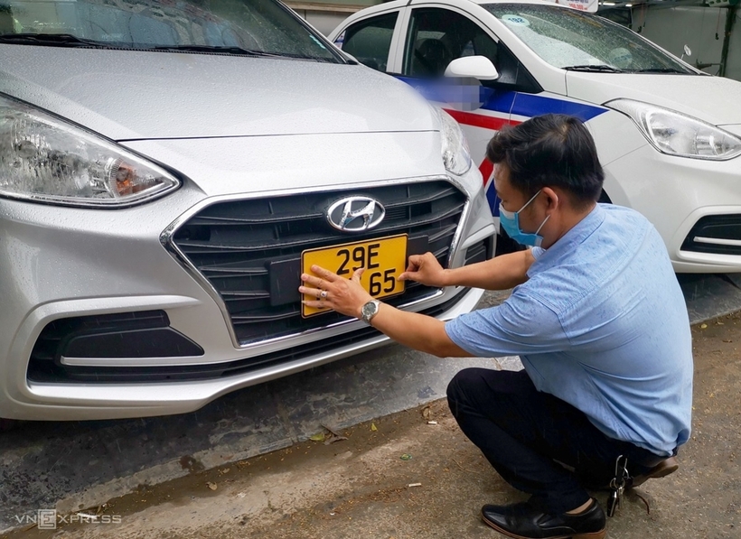 Một tài xế xe taxi tại Hà Nội gắn biển màu vàng lên xe. Ảnh: VnExpress