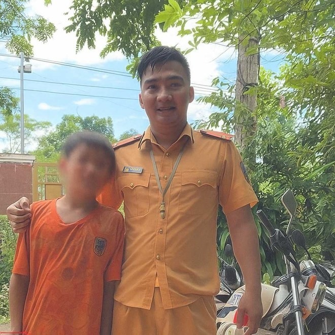 Thượng úy Tạ Quang Quyết và cháu bé được anh cứu sống từ dòng nước xiết. Ảnh: Lao động