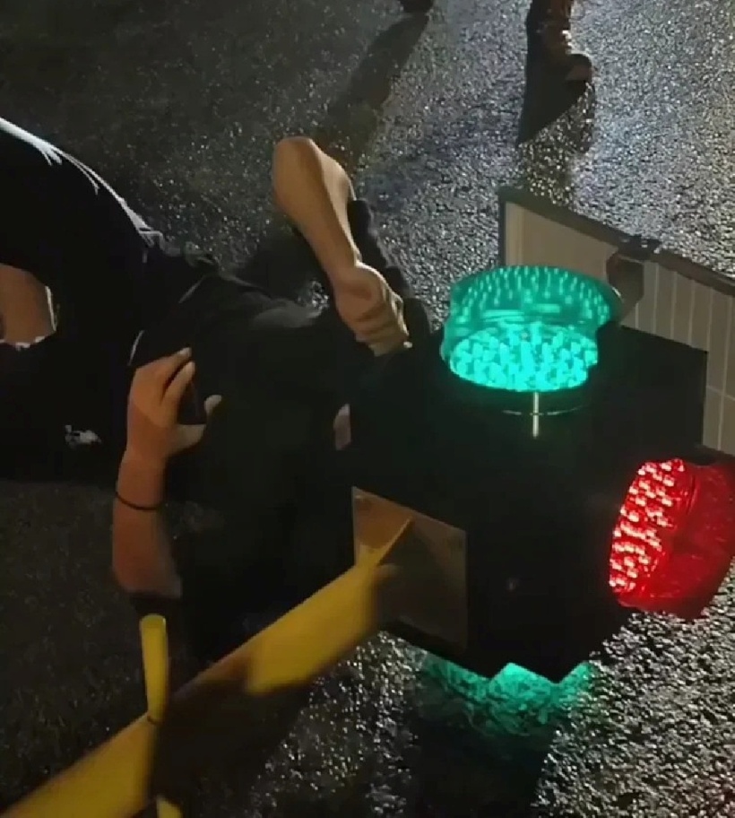 Dù nửa đầu bị kẹt trong cột đèn giao thông, người đàn ông vẫn bình tĩnh lướt điện thoại trong khi chờ lực lượng cứu hộ tới giải cứu. Ảnh: Vietnamnet.