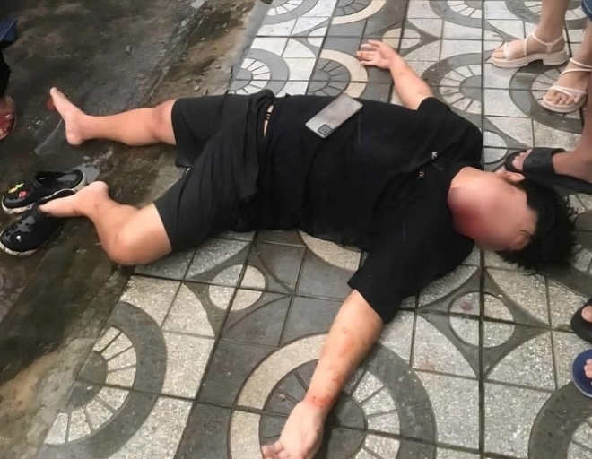 Tài xế xe công nghệ bị đánh bất tỉnh, nằm trên vỉa hè. Ảnh: Người lao động