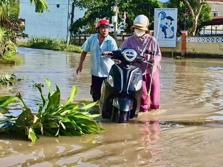 Người dân xã Đồng Xuân, Đắk Lắk lội trong dòng nước lũ sau bão số 13. (Ảnh: Tuổi trẻ)