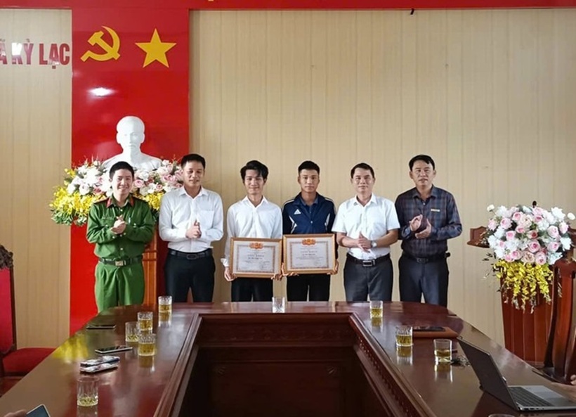 Nam sinh Phan Bình Minh (áo khoác đen) cùng anh Phan Lương Nhật nhận giấy khen của Chủ tịch UBND xã Kỳ Lạc vì đã có hành động dũng cảm cứu người đuối nước. Ảnh: Tuổi trẻ Online