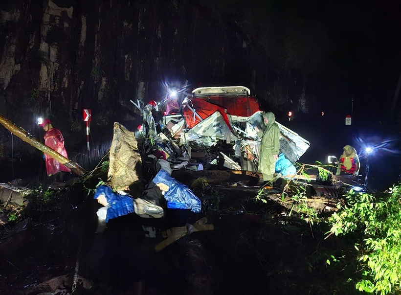 Tại hiện trường, cabin bị đất đá tách rời, thân bên phải ôtô biến dạng, vỡ kính, khung sắt và giường nằm méo mó. Nhiều người mắc kẹt bên trong. Đất đá cũng vùi nhiều xe máy gần đó. (Ảnh: VnExpress)