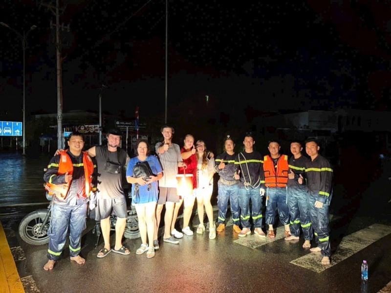 3 du khách Nga được ứng cứu ra khỏi vùng ngập lụt cùng các đồng hương chụp ảnh với tổ công tác của Phòng Cảnh sát PCCC&CNCH Công an tỉnh Khánh Hoà trước khi về lại nơi lưu trú tại một khách sạn ở phường Nha Trang. Ảnh: Công an nhân dân