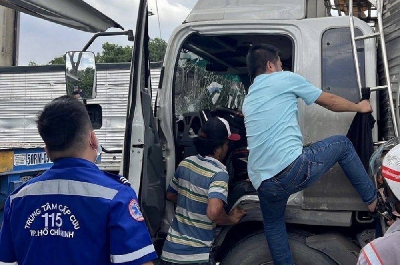 Tài xế và người đi đường dừng xe tìm cách phá cửa cabin chuyển tài xế ra ngoài. Ảnh: Báo Công an Nhân dân.