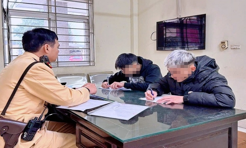 Cảnh sát làm việc với hai thanh niên vi phạm.