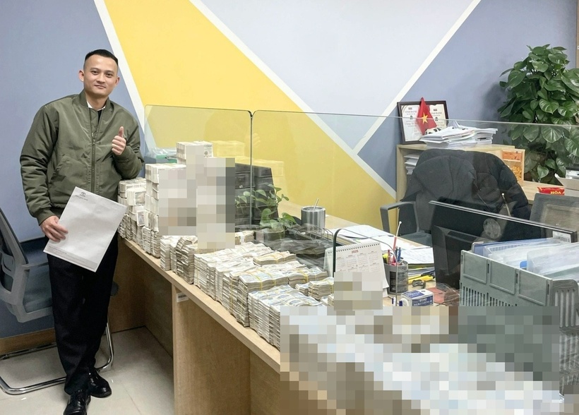 Anh Hoàng Hiệp - nhân viên bán ô tô - đứng cạnh các cọc tiền do khách hàng đưa đến. Ảnh: Dân trí