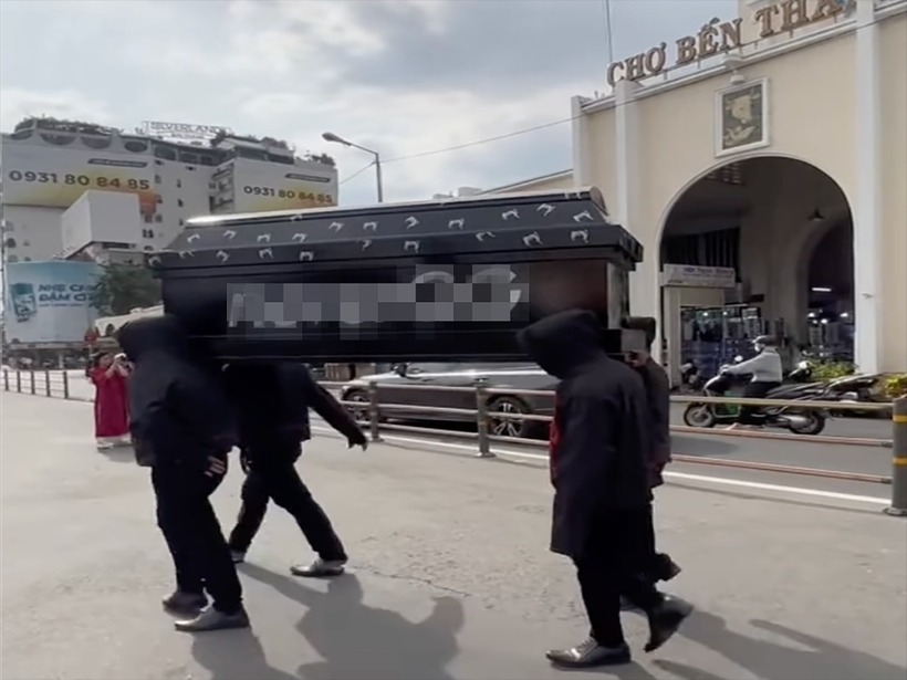 Nhóm thanh niên khiêng quan tài đi qua lại trước chợ Bến Thành. (Ảnh: VnExpress)