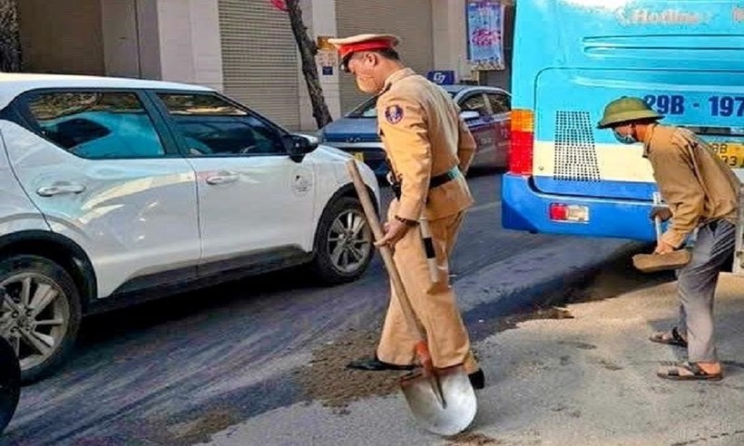Cảnh sát và người dân dùng cát khắc phục vết dầu loang, bảo đảm an toàn giao thông.