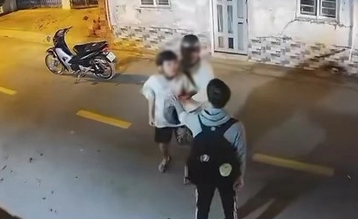 Hai nam thanh niên (đội mũ bảo hiểm) lao vào đánh nam sinh (đeo balo đen) tới tấp. Ảnh: Tuổi trẻ