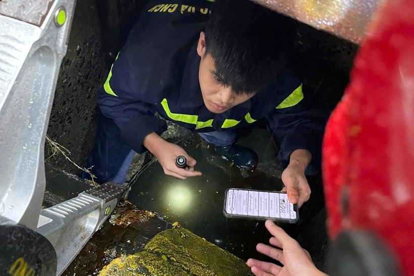 Một chiến sĩ công an chui xuống cống tìm điện thoại cho du khách. (Ảnh: Công an Đà Nẵng)