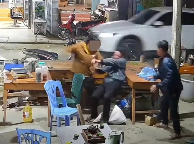 Hình ảnh bà N.T.H. mặc áo vàng cầm dao đâm chồng mình, một hàng xóm cố gắng can ngăn nhưng không thành. (Ảnh: Dân trí)