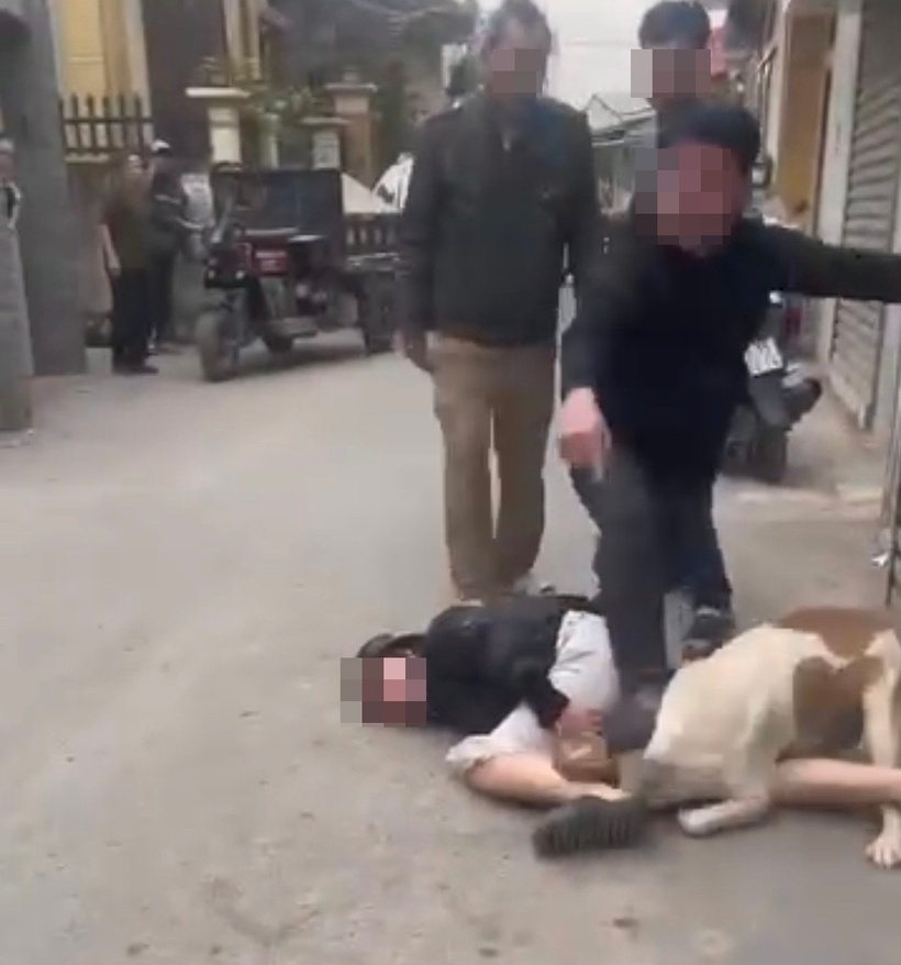 Con chó vẫn không chịu rời đi mà còn cắn vào chân người phụ nữ, khiến nạn nhân kêu cứu thảm thiết. Ảnh: Báo Tiền phong.