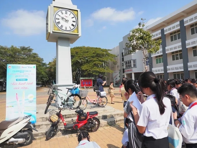 Học sinh trải nghiệm tại trạm 1 với hình ảnh chiếc đồng hồ được đặt bên cạnh một chiếc xe đạp cũ, một xe đạp điện, một xe máy. (Ảnh: Dân Trí).