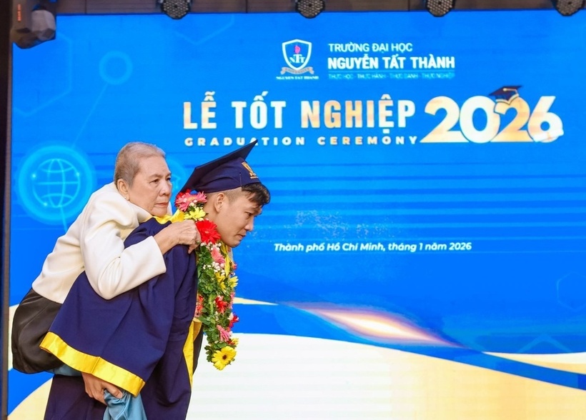 Phạm Trung Trí Dũng cõng mẹ lên sân khấu nhận bằng tốt nghiệp đại học cùng mình. (Ảnh: Trường ĐH Nguyễn Tất Thành).