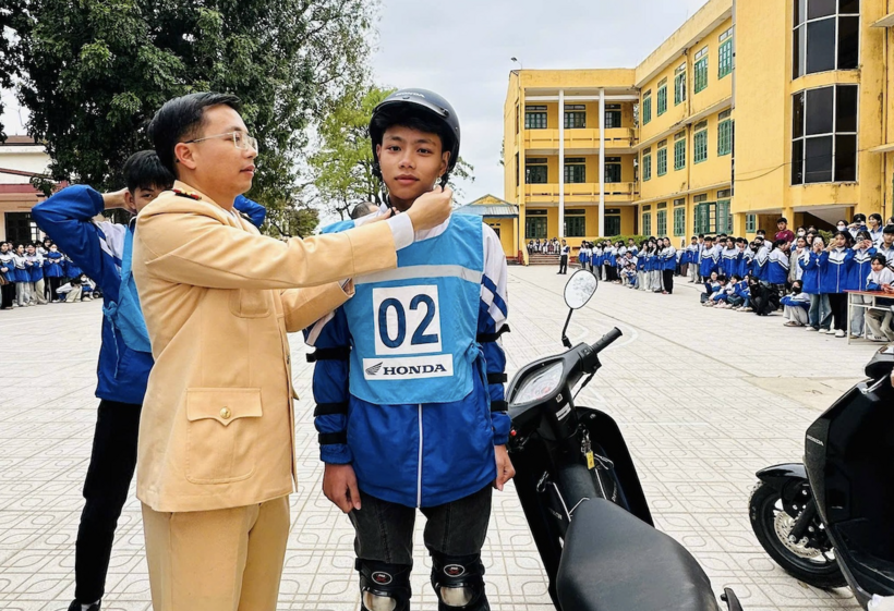 Cán bộ CSGT hướng dẫn các em học sinh đội mũ bảo hiểm đúng cách. Ảnh CACC