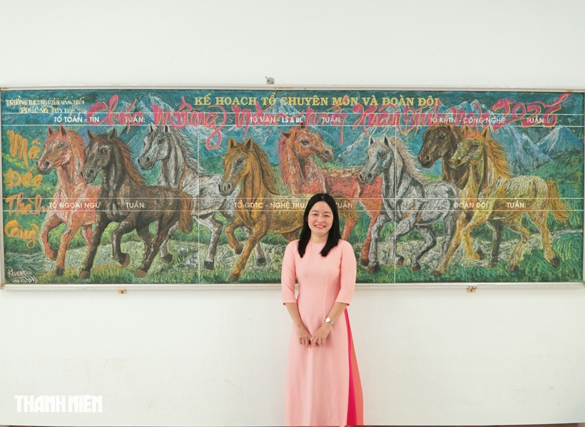 Cô Trâm bên tác phẩm "mã đáo thành công" trên nền bảng. Ảnh: Thanh niên