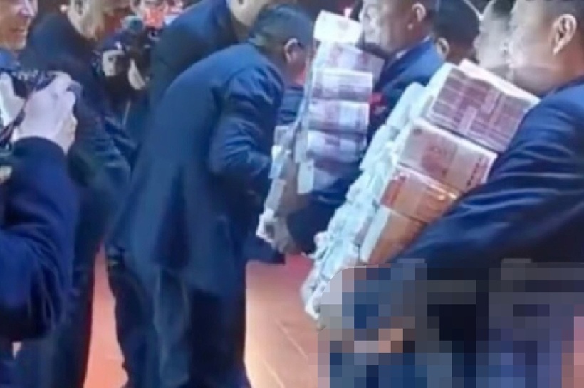 Nhiều nhân viên ôm từng bó tiền dày trên sân khấu, thậm chí không thể cầm hết bằng hai tay. Ảnh: Elephant News.
