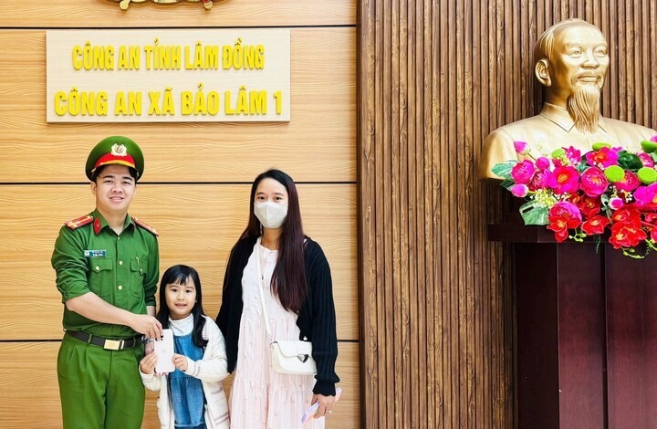 Cháu Thục Anh trao chiếc điện thoại nhặt được cho các chú công an và nhờ trả lại cho người đánh rơi. (Ảnh: Cơ quan công an)
