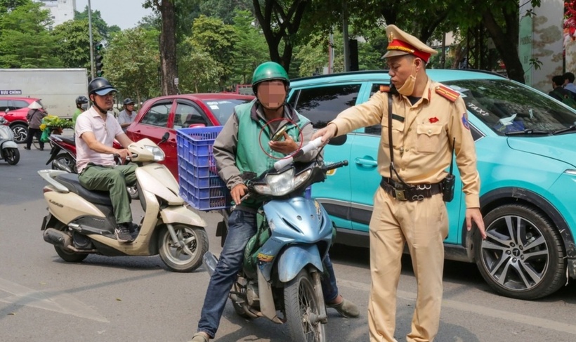 Cảnh sát giao thông yêu cầu dừng xe một người giao hàng có hành vi sử dụng điện thoại khi đang điều khiển xe máy. (Ảnh: Dân trí)