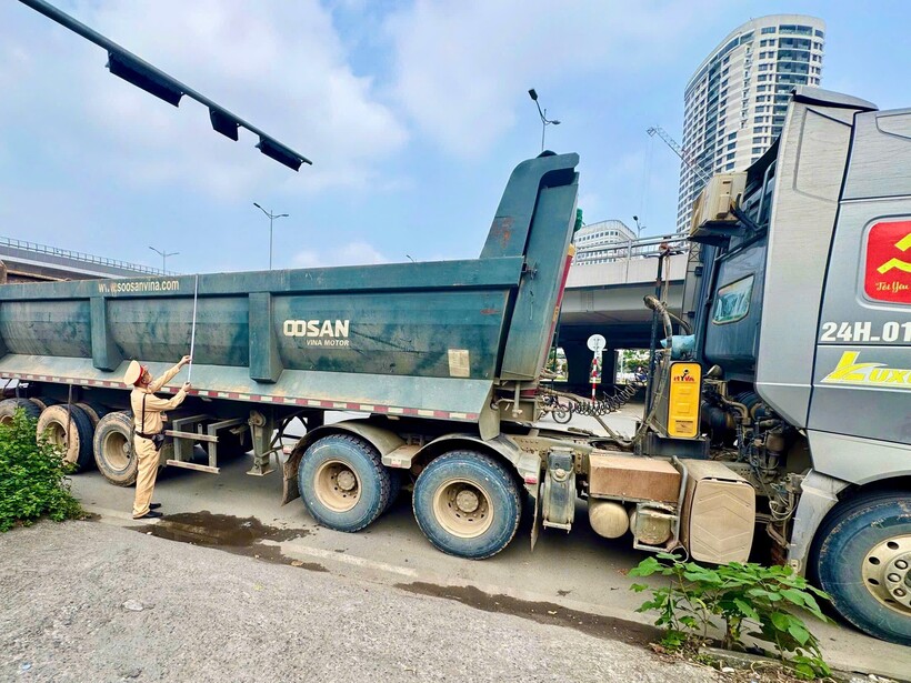 Cảnh sát kiểm tra chiếc xe đầu kéo làm rơi đất thải trên đường.