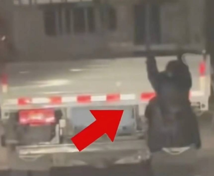 Người phụ nữ dùng hai tay bám chặt vào thành xe, toàn thân ở ngoài thùng. Ảnh: Sohu.