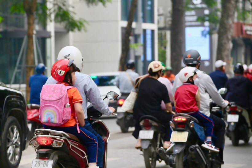 Nhiều người dân chấp hành tốt quy định đội mũ bảo hiểm cho con khi tham gia giao thông.