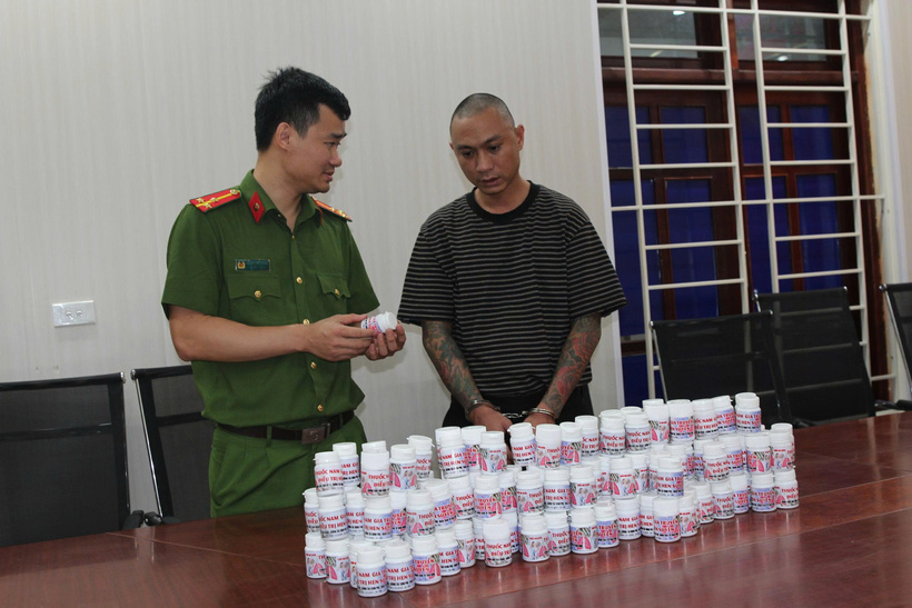 Nguyễn Duy Sơn cùng tang vật là những lọ thuốc chữa hen suyễn giả, tại cơ quan điều tra.