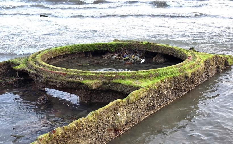 Vật thể nghi xác xe tăng phát lộ khi thủy triều rút. (Ảnh: VnExpress)