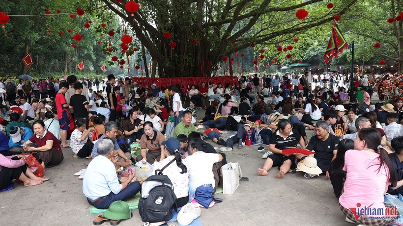 Thời tiết oi bức khiến hành trình hành hương thêm phần vất vả. Dọc các lối đi, nhiều người chọn nghỉ chân dưới tán cây, bãi cỏ để tránh nắng, lấy lại sức. Ảnh: VietNamNet.