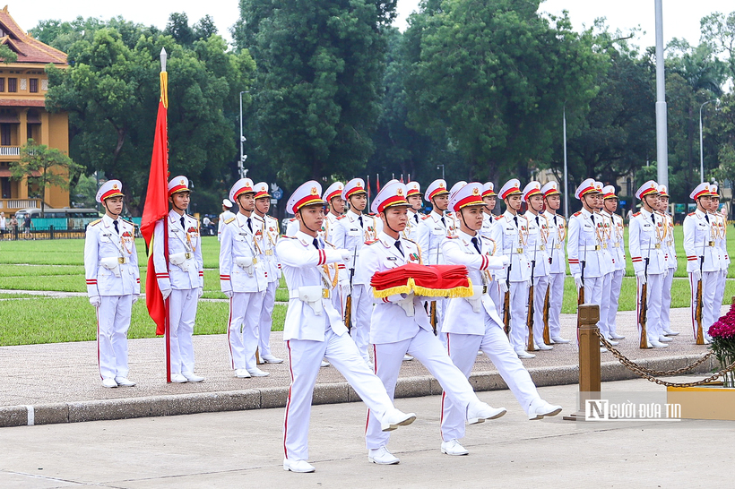 Ba chiến sĩ mang khay đựng quốc kỳ tách khỏi đội hình tiến về cột cờ, chuẩn bị các nghi thức trang trọng.